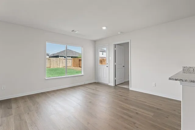 an empty room with wooden floor cabinet and windows