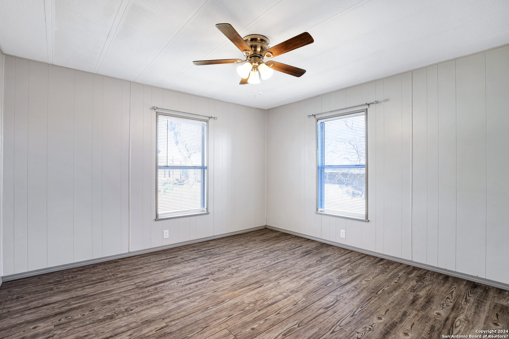 18066 La Gloria Road Elmendorf, TX 78112 - Photo 19 of 24 an empty room with wooden floor and windows