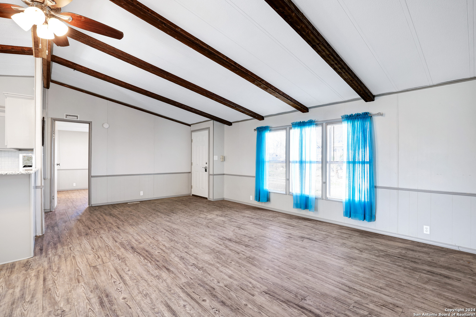 18066 La Gloria Road Elmendorf, TX 78112 - Photo 6 of 24 a view of an empty room with wooden floor and entryway