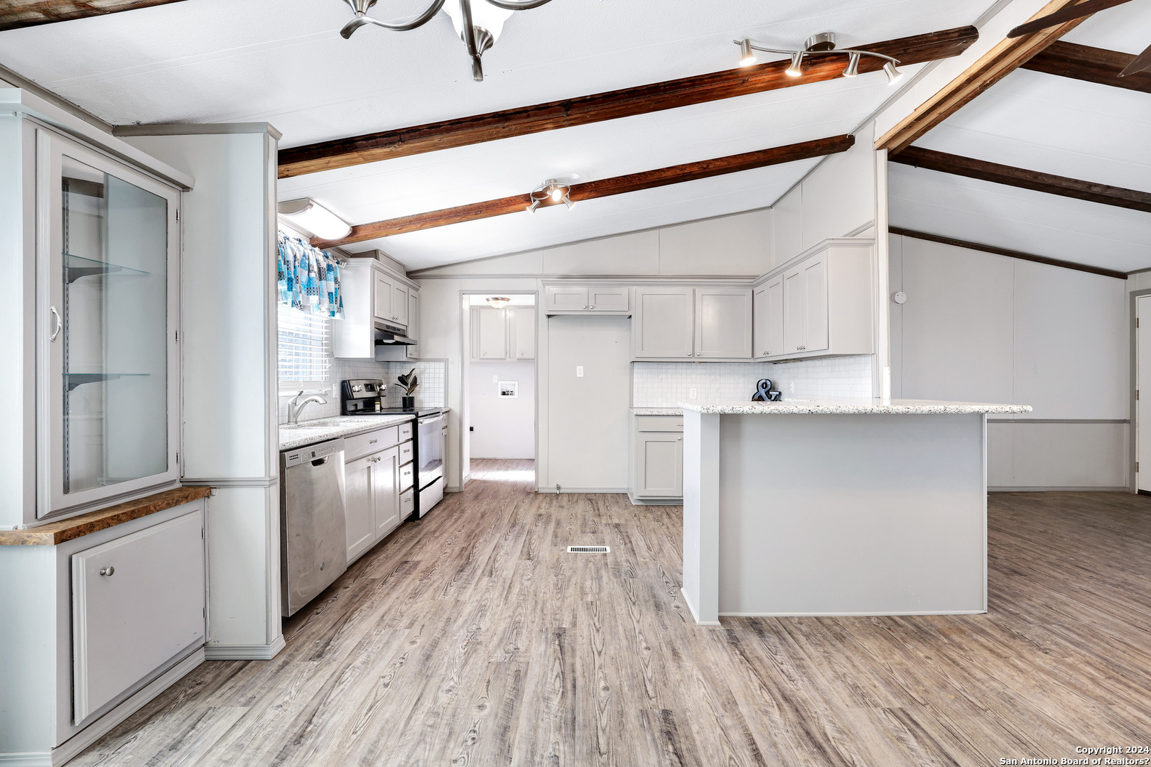 18066 La Gloria Road Elmendorf, TX 78112 - Photo 10 of 24 a kitchen with cabinets wooden floor and stainless steel appliances