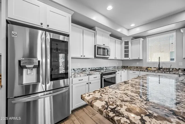 a kitchen with kitchen island a counter top space stainless steel appliances and cabinets