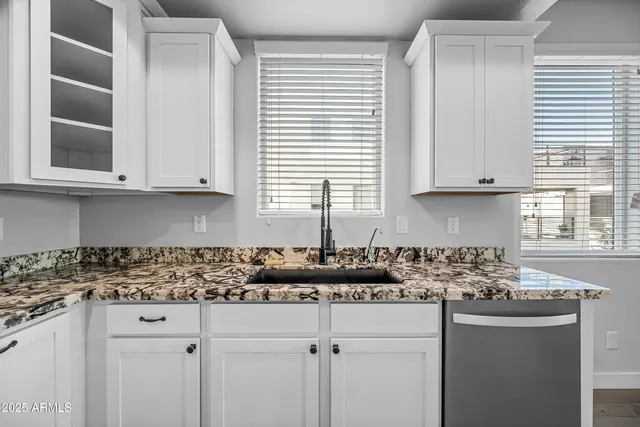 a kitchen with stainless steel appliances granite countertop white cabinets sink and window