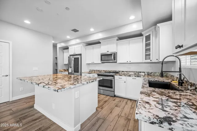 a kitchen with stainless steel appliances granite countertop a sink stove and refrigerator