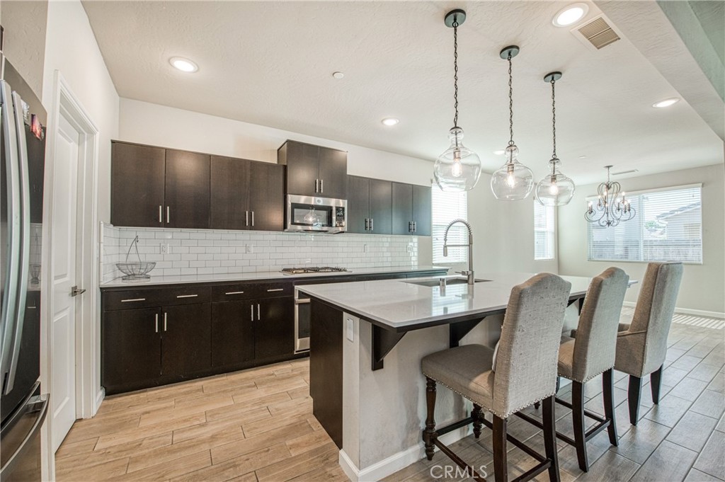 4135 Mecca Avenue Clovis, CA 93619 - Photo 10 of 32 a kitchen with stainless steel appliances kitchen island granite countertop a kitchen island hardwood floor sink and stove