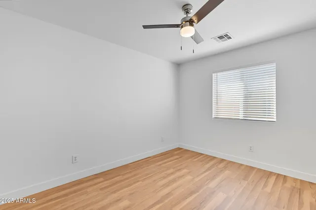 an empty room with wooden floor closet and windows