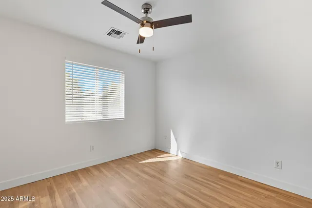 an empty room with wooden floor closet and windows