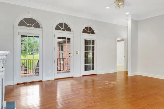a view of an empty room with window and wooden floor