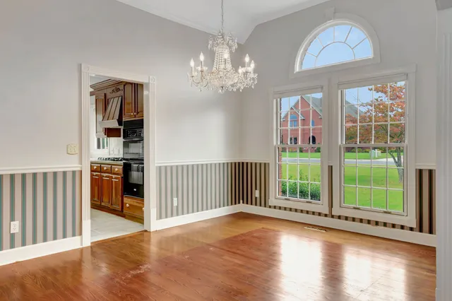 a view of a livingroom with wooden floor stairs and a chandelier