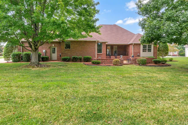 a front view of a house with a garden and trees