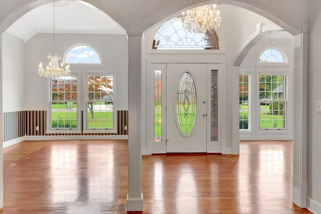 a view of a room with wooden floor a chandelier and windows