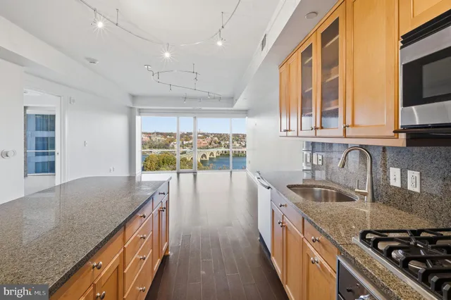 a kitchen with stainless steel appliances granite countertop a sink a stove and a wooden cabinets