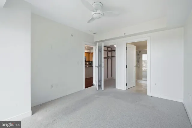 an empty room with closet and a ceiling fan