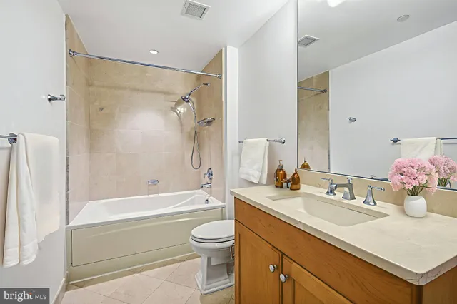 a bathroom with a bathtub shower sink vanity mirror and toilet