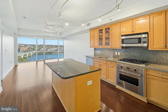 a kitchen with stainless steel appliances granite countertop a stove a sink and a microwave