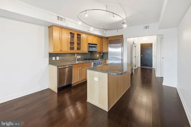 a kitchen with stainless steel appliances granite countertop a sink a stove and a wooden floors
