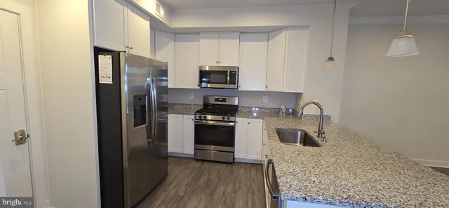 a kitchen with stainless steel appliances granite countertop a refrigerator stove and sink
