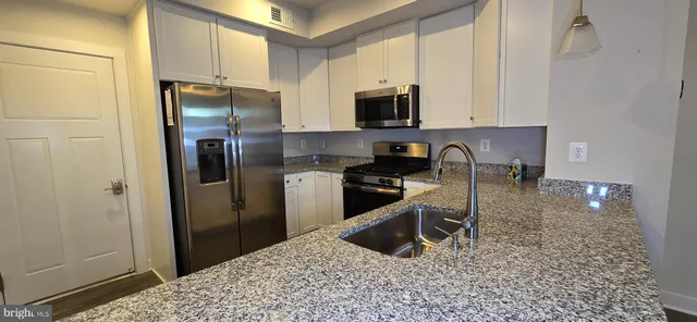 a kitchen with stainless steel appliances granite countertop a sink a stove and a refrigerator