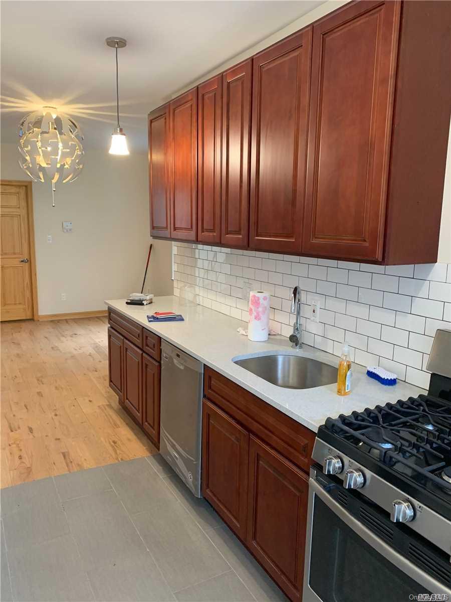 2906 Fulton Street, Unit 2 Brooklyn, NY 11207 - Photo 1 of 1 a kitchen with granite countertop stainless steel appliances a sink a stove cabinets and a kitchen island
