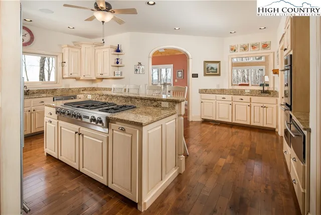 a kitchen with stainless steel appliances granite countertop hardwood floor sink stove and wooden floor