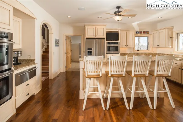 a kitchen with stainless steel appliances granite countertop a dining table chairs refrigerator and sink
