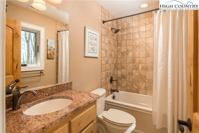 a bathroom with a granite countertop sink toilet a mirror and shower