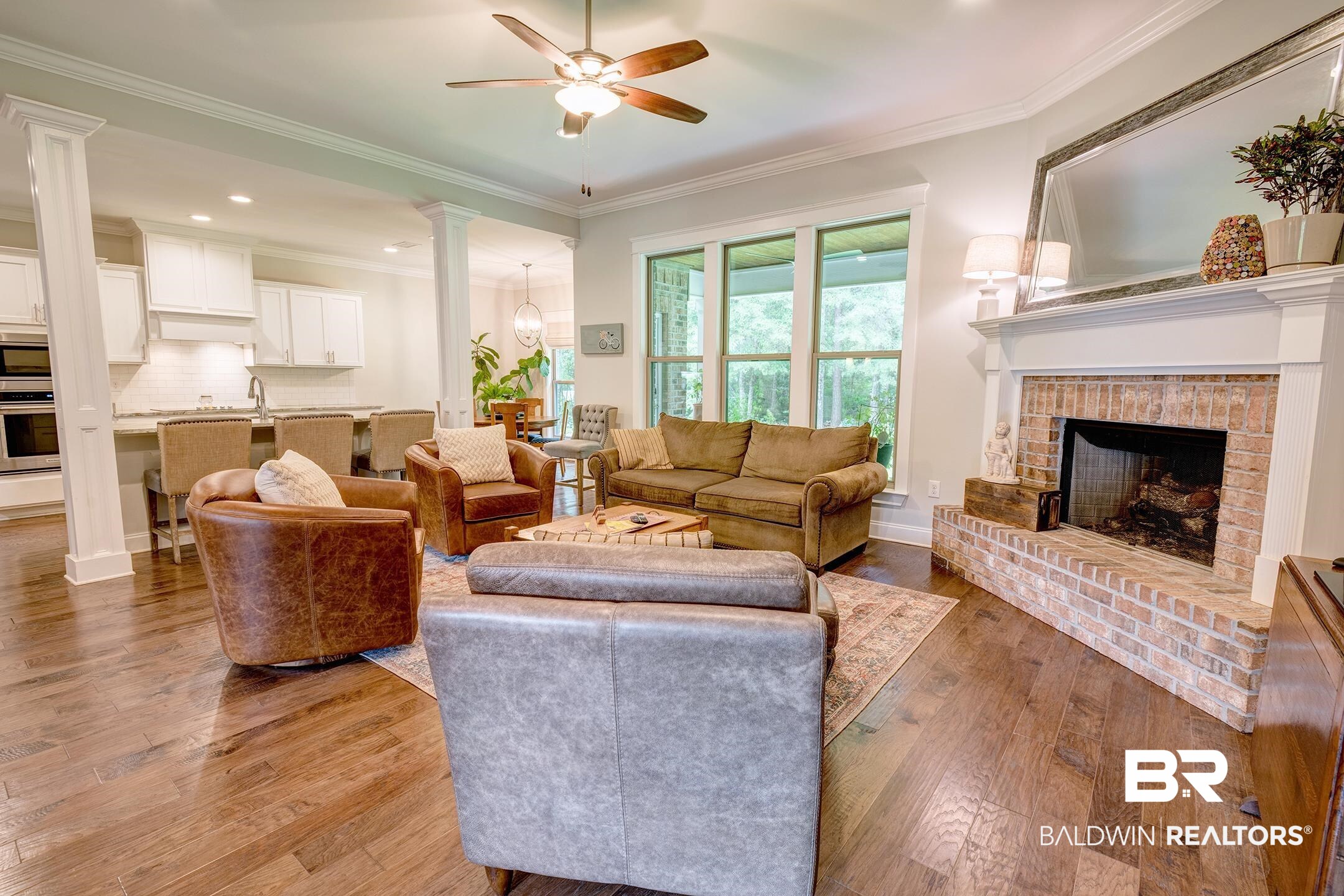 18754 Treasure Oaks Road Gulf Shores, AL 36542 - Photo 28 of 53 Spacious living area featuring wood-finish flooring, a brick-surround fireplace with a white mantel, and large windows