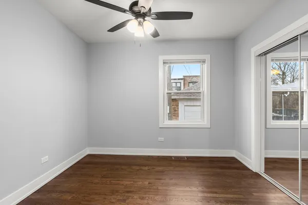 an empty room with wooden floor fan and windows