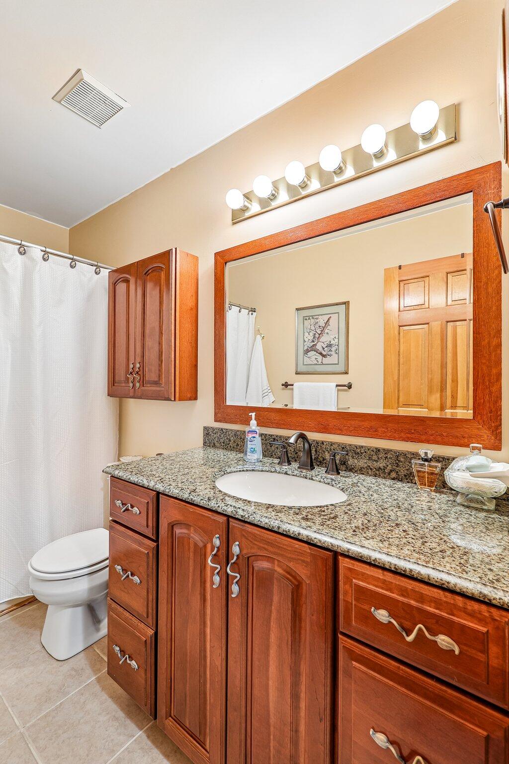 1317 Cayton Road Florence, KY 41042 - Photo 30 of 36 Wood-finish vanity with an integrated sink, stone countertop, and wall-mounted mirror