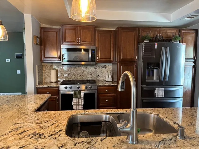 a kitchen with stainless steel appliances granite countertop a refrigerator a stove top oven a sink and dishwasher