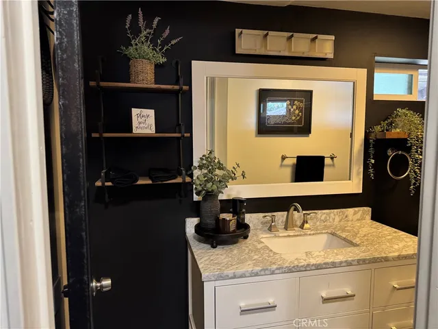 a bathroom with a granite countertop sink a mirror and vanity