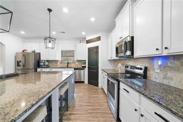 a kitchen with white cabinets and stainless steel appliances