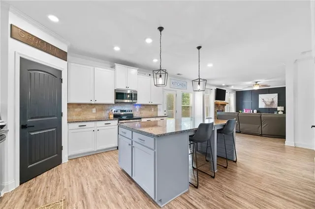 a kitchen with kitchen island granite countertop a sink a counter space appliances and cabinets