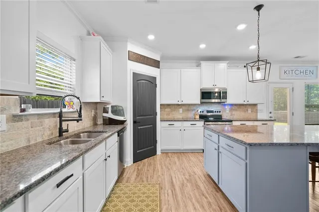 a kitchen with kitchen island wooden floor center island and stainless steel appliances