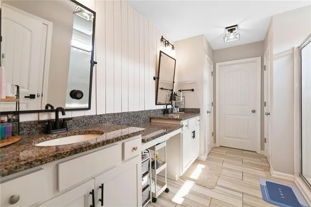 a bathroom with a granite countertop sink a mirror and a shower