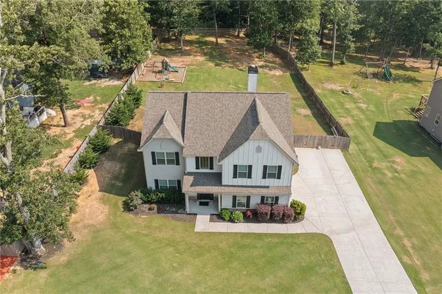 an aerial view of a house with swimming pool and large trees