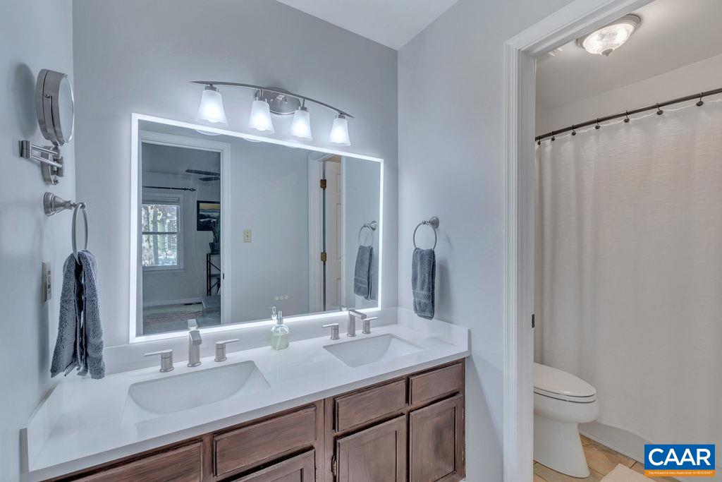 1436 Minor Ridge Court Charlottesville, VA 22901 - Photo 33 of 59 a bathroom with a granite countertop sink a toilet and a large mirror