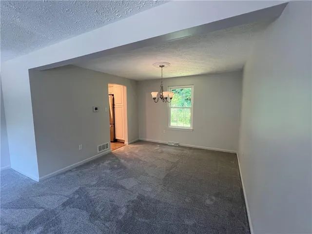 an empty room with windows and chandelier fan