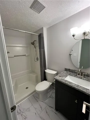 a bathroom with a granite countertop sink toilet a mirror and shower