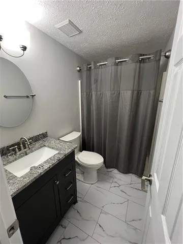 a bathroom with a granite countertop sink toilet and shower