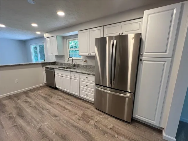 a kitchen with stainless steel appliances a refrigerator a sink and white cabinets