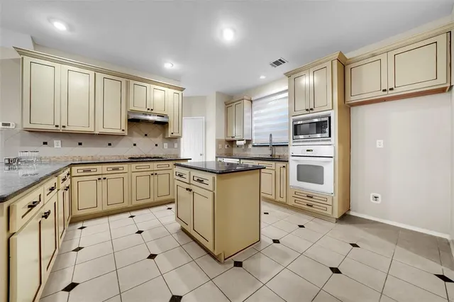 a kitchen with kitchen island granite countertop a stove sink and cabinets