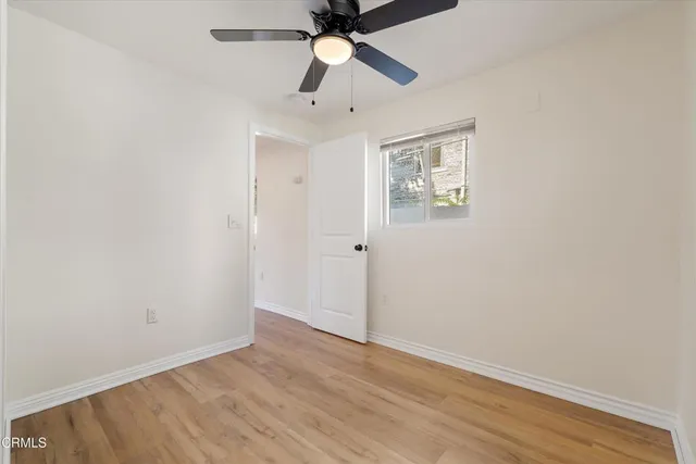 an empty room with a window and a ceiling fan