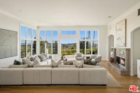 a living room with furniture large window and wooden floor