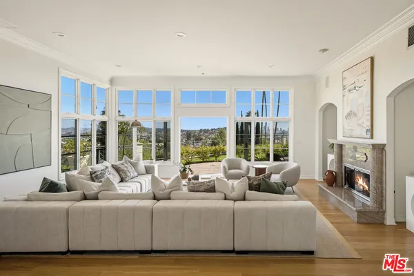 a living room with furniture large window and wooden floor