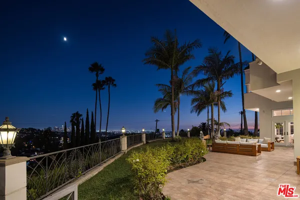 a view of a patio with couches chairs and a floor to ceiling window next to a yard