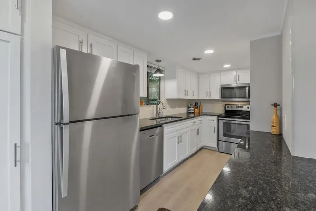 a kitchen with granite countertop a sink stainless steel appliances and cabinets