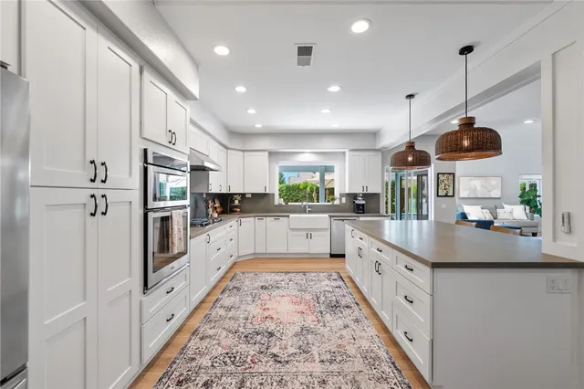 a large kitchen with stainless steel appliances kitchen island granite countertop a refrigerator a oven and a sink