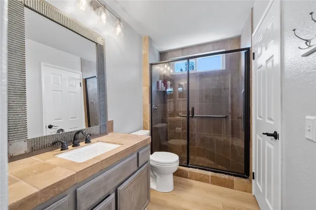 a bathroom with a granite countertop sink toilet a mirror and shower