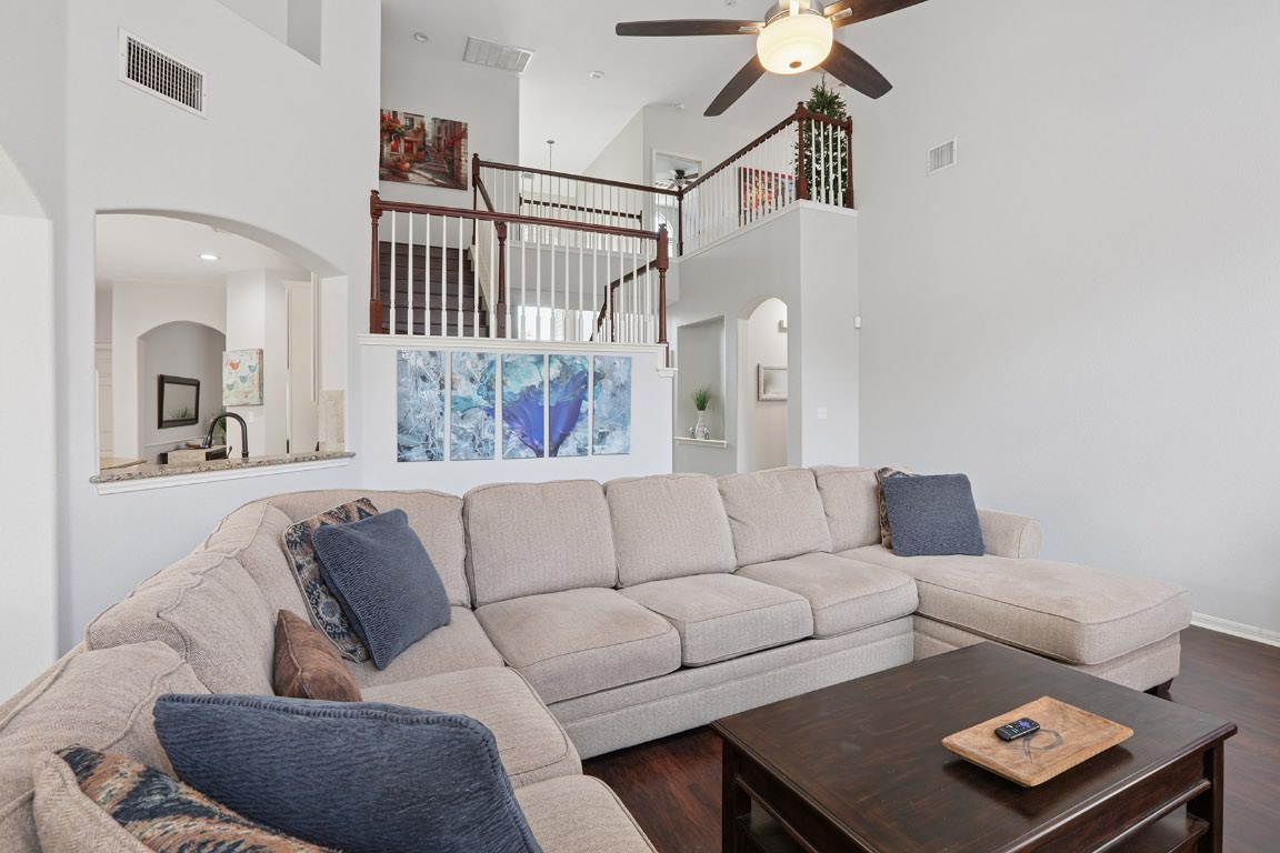 11217 Terrace Meadow Way Manor, TX 78653 - Photo 12 of 33 Living room featuring a towering ceiling, arched walkways, a ceiling fan, wood finished floors, and stairs