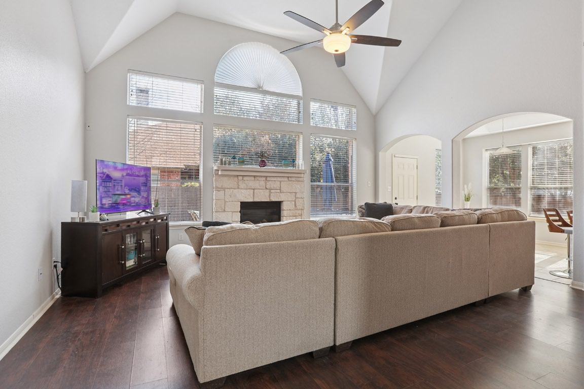 11217 Terrace Meadow Way Manor, TX 78653 - Photo 13 of 33 Living room featuring high vaulted ceiling, a stone fireplace, dark wood-style floors, and ceiling fan